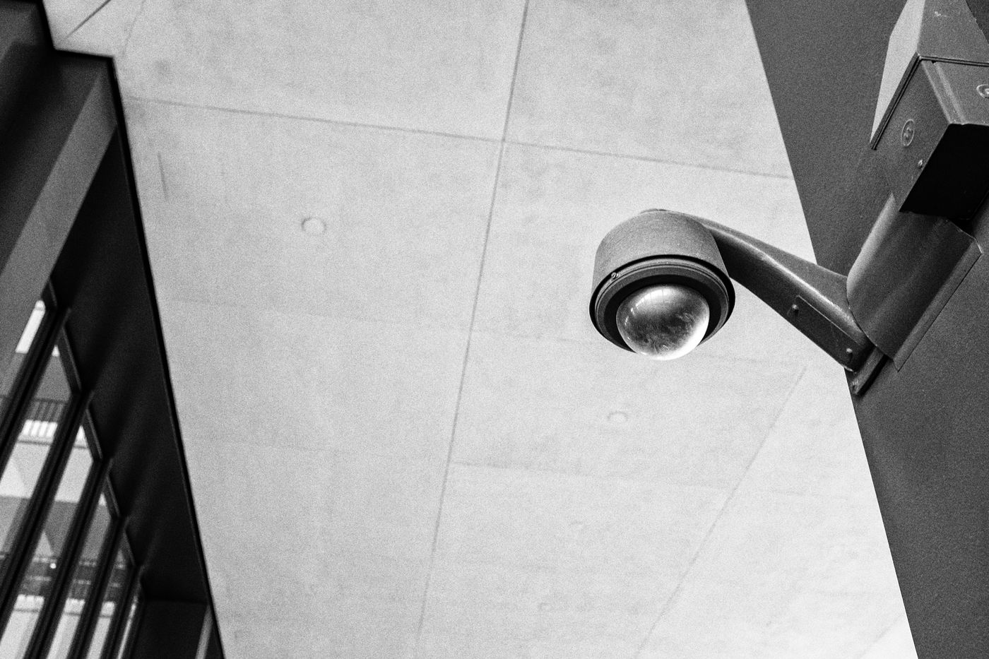Black and white photo of a dome surveillance camera on a building wall