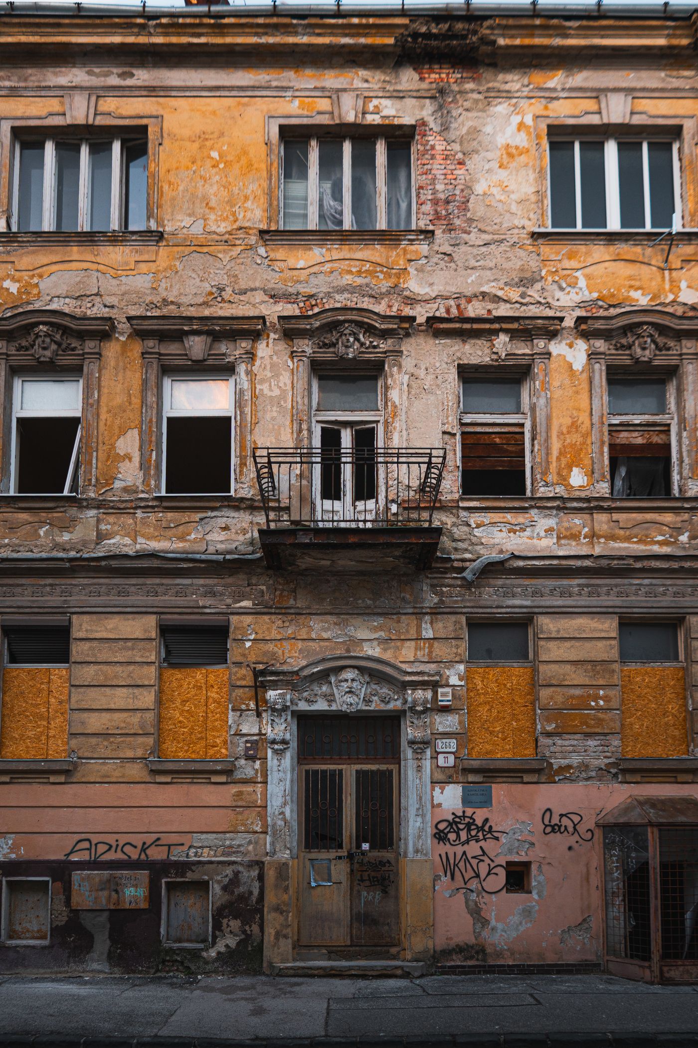 A decayed building facade with peeling plaster and boarded windows
