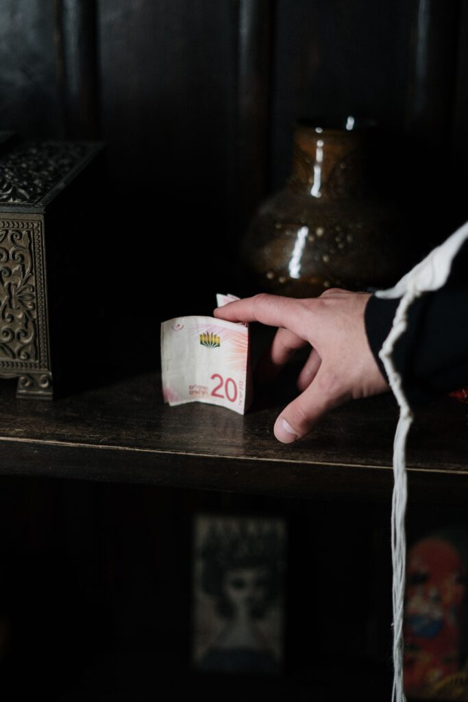 A hand sliding a banknote across a dark wooden shelf