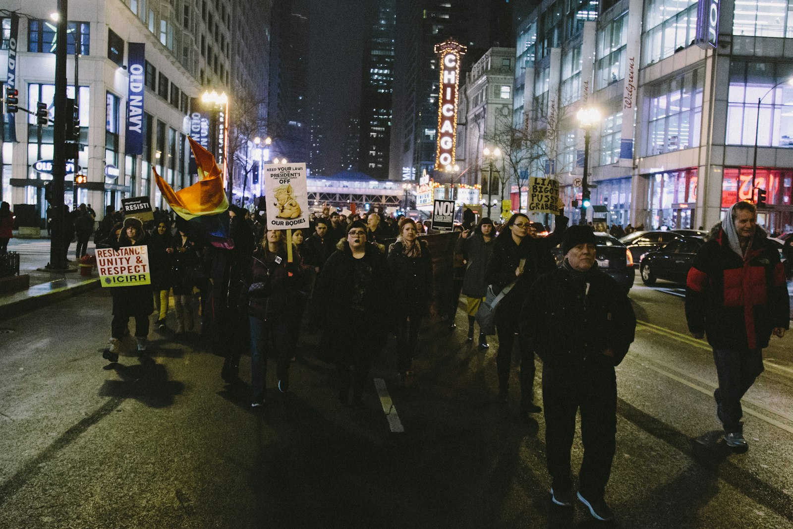 A crowd with signs marching down a city street at night