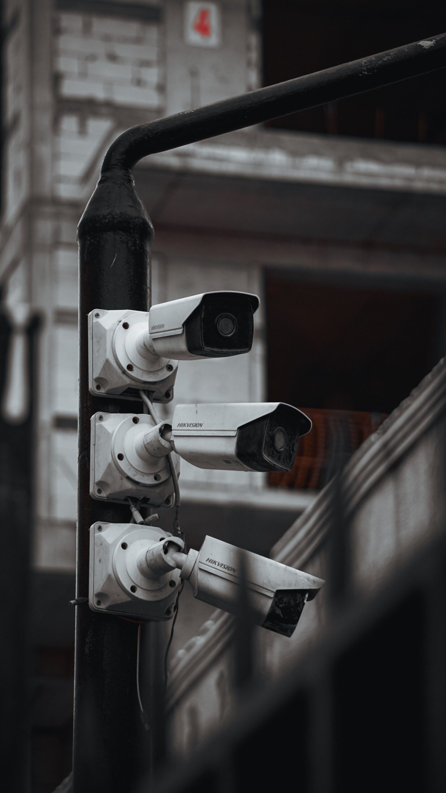 Three surveillance cameras mounted on a pole in black and white